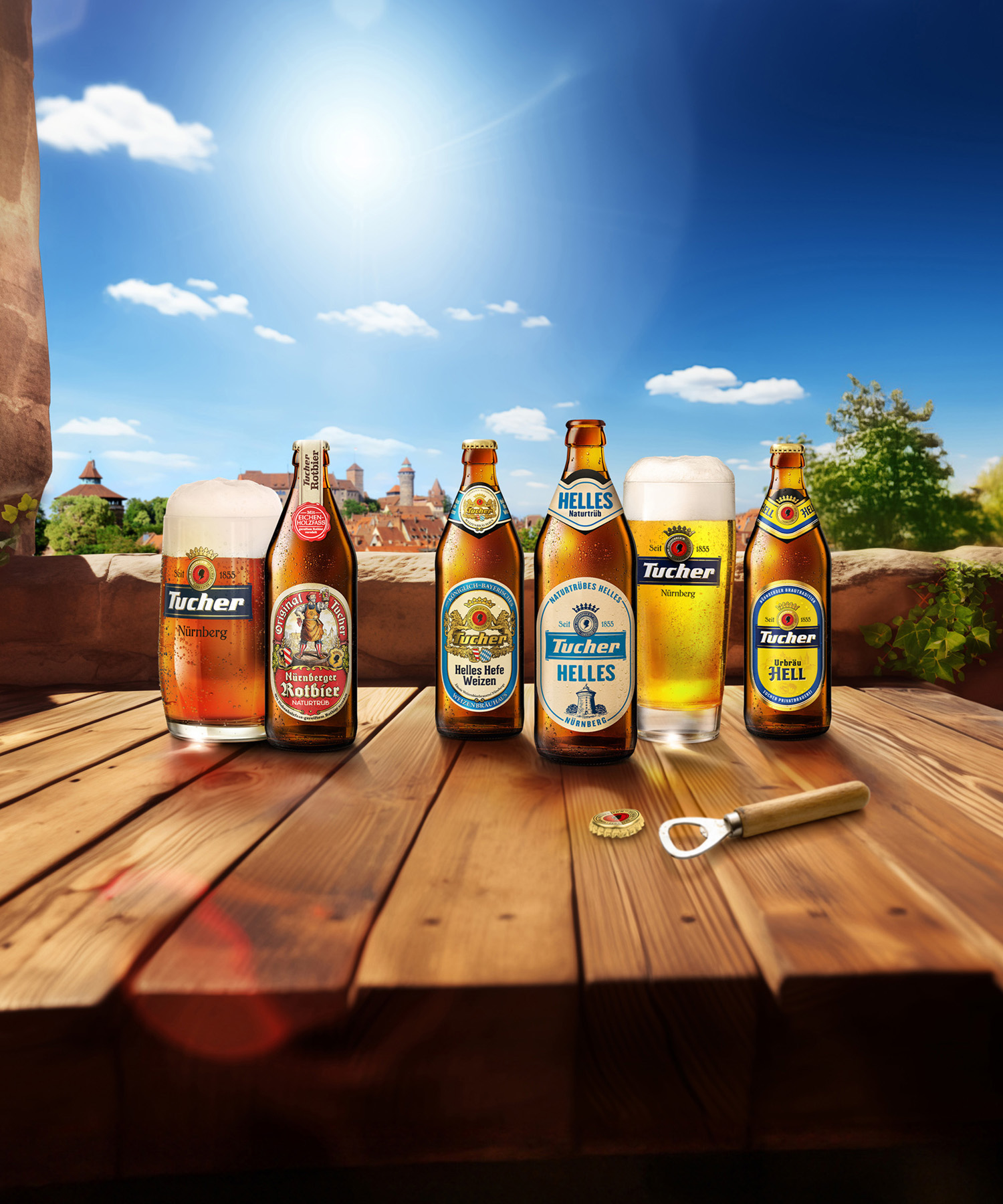 Fünf Flaschen und ein Glas Bier stehen auf einem Holztisch vor einer sonnigen Landschaft.