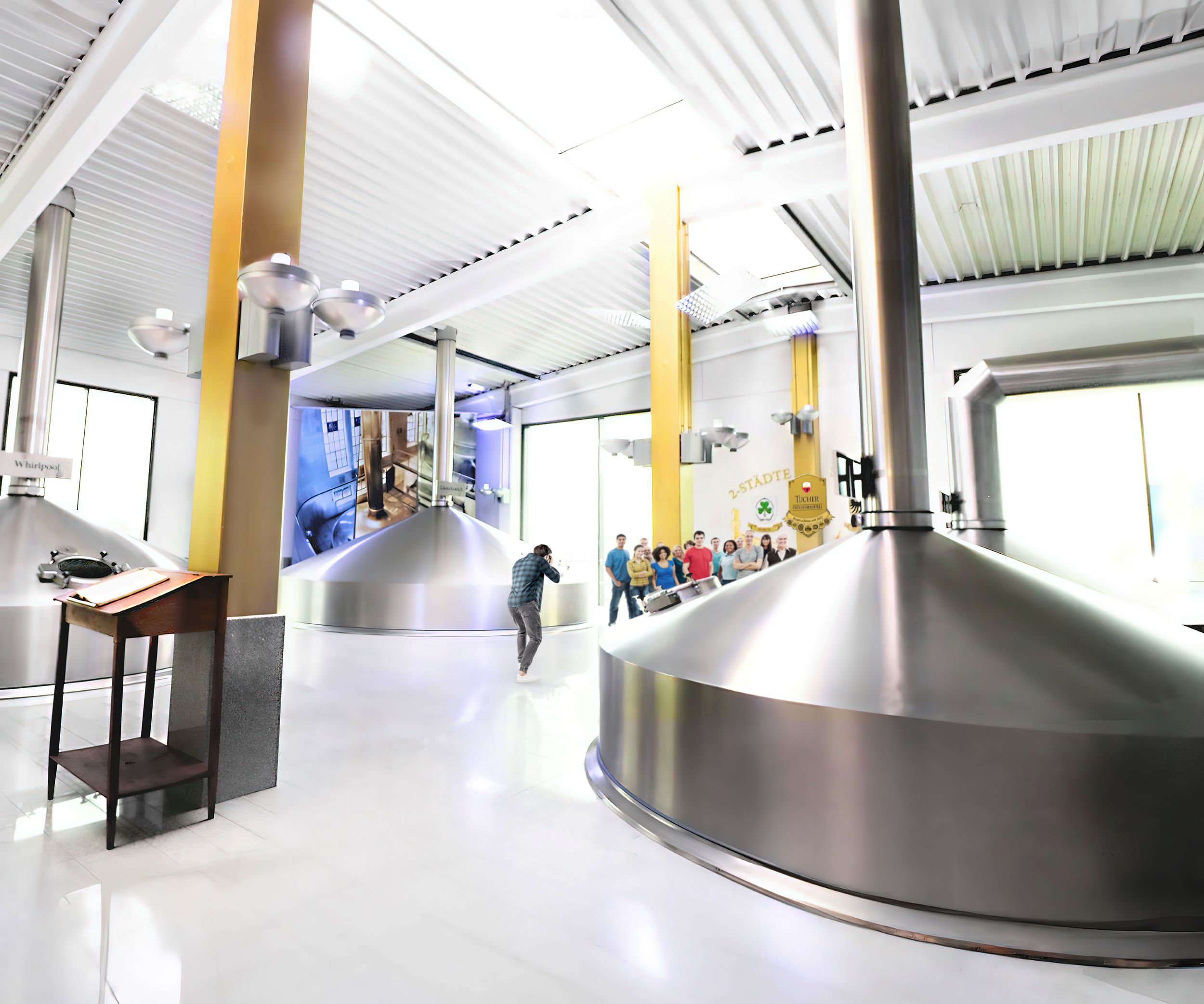 Eine Person fotografiert große Braukessel in einem industriellen Brauereiraum.